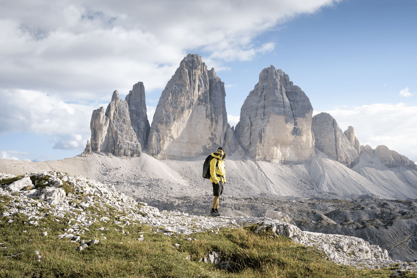 A man wearing a backpack looking sideways, and mountain range scenery in the background