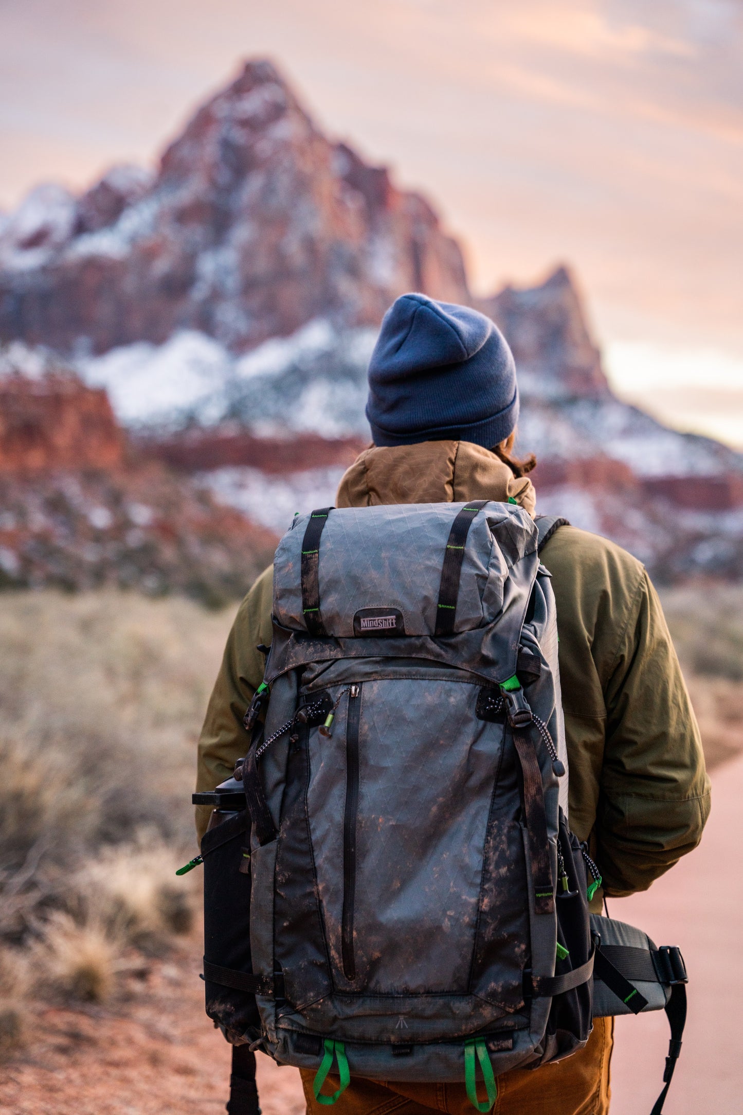 A man wearing a backpack, and a out of focus view of a mountain in the distance
