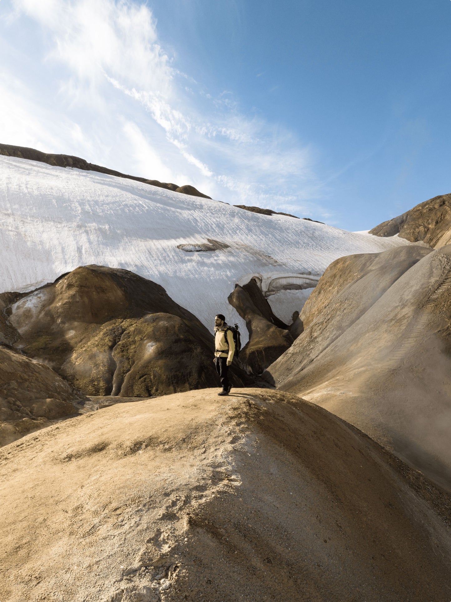 Highlands of Iceland scenery with a man standing on a boulder wearing a backpack