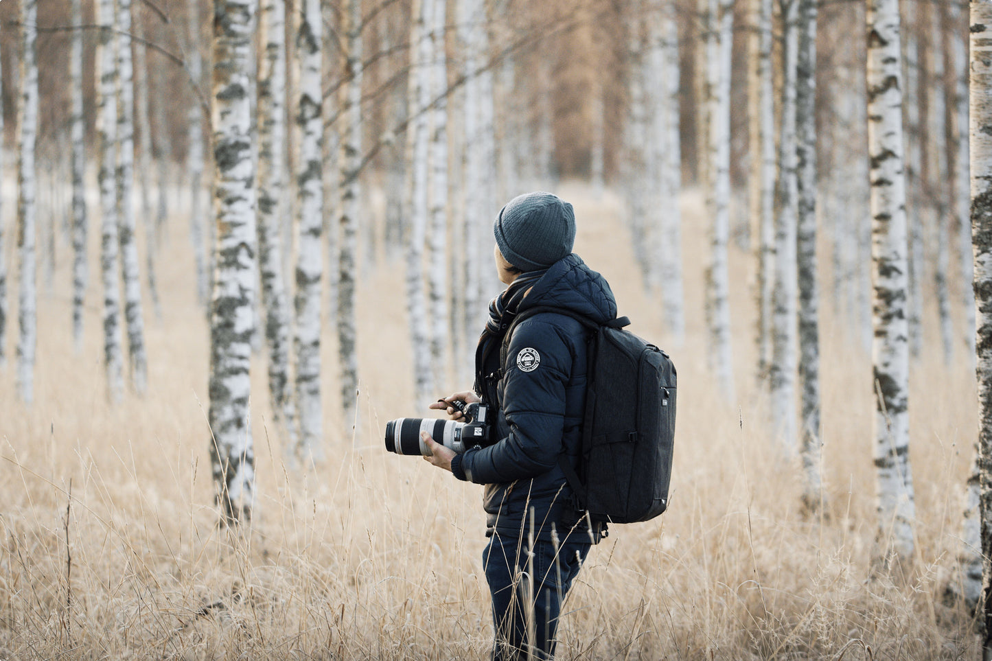 A photographer wearing a backpack and holding camera equipment 
