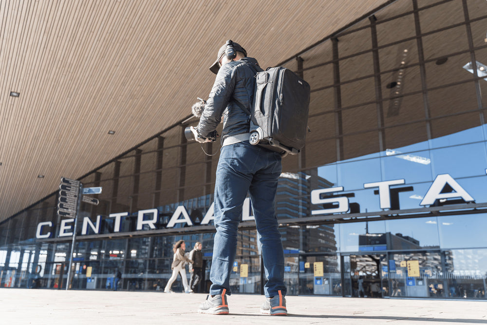 A man wearing a roller backpack, holder camera equipment and wearing headphones