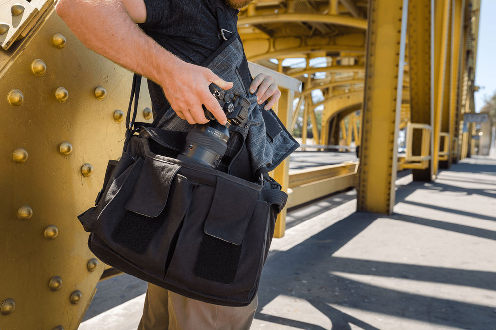 A photographer reaching into a black camera bag and grabbing his camera gear out